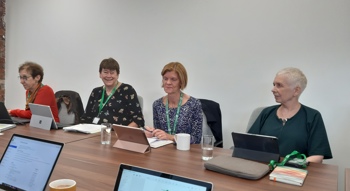 A group of people sitting around a board table in a meeting setting